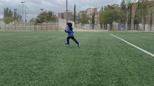Child running on football pitch to the football for fun